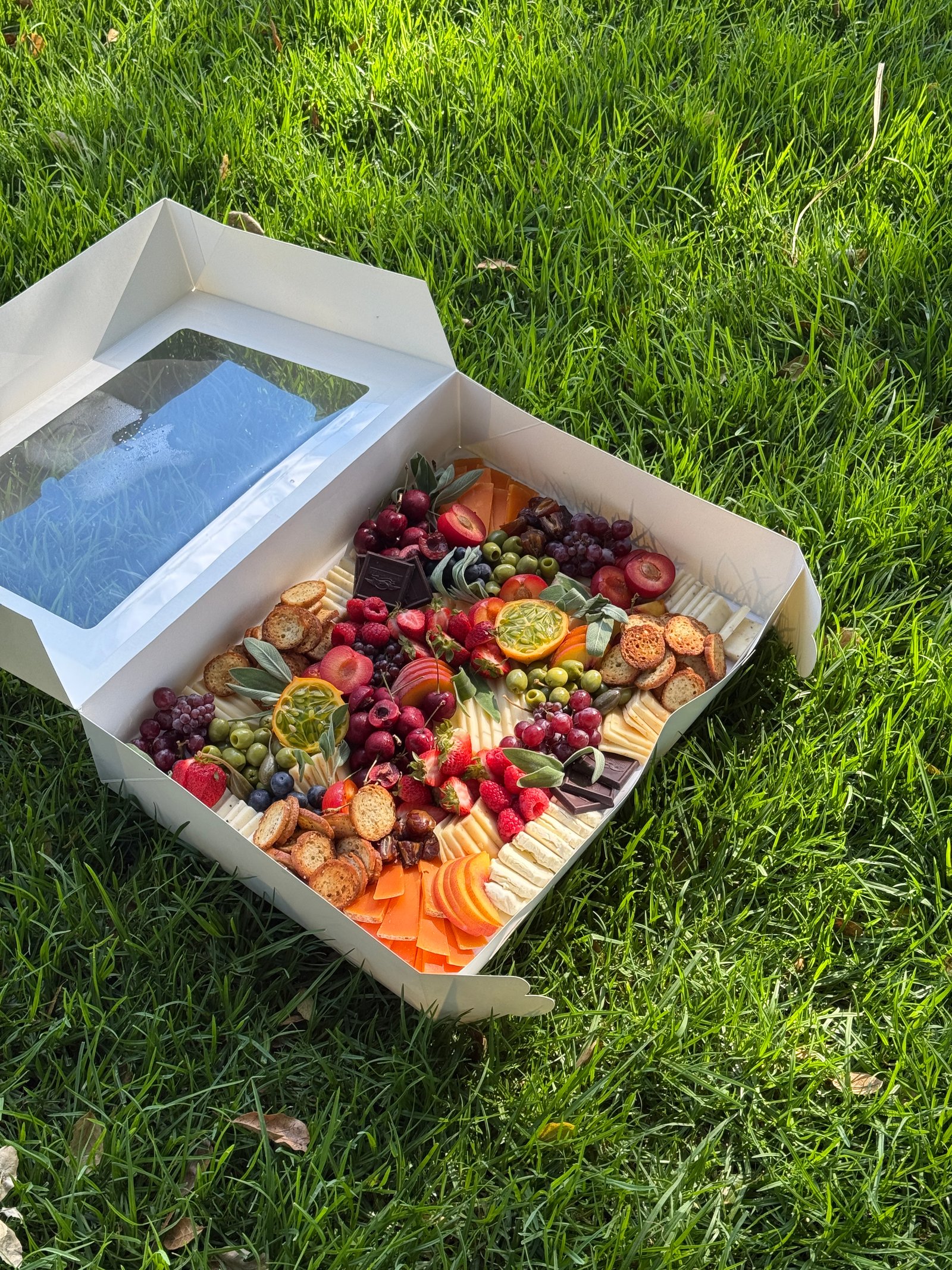 Outdoor charcuterie picnic setup with fruits and meats